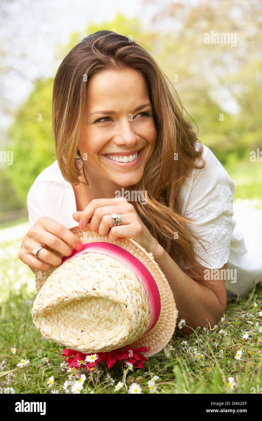 Woman Lying In Field Of Summer Flowers With Straw Hat Stock Photo - Alamy