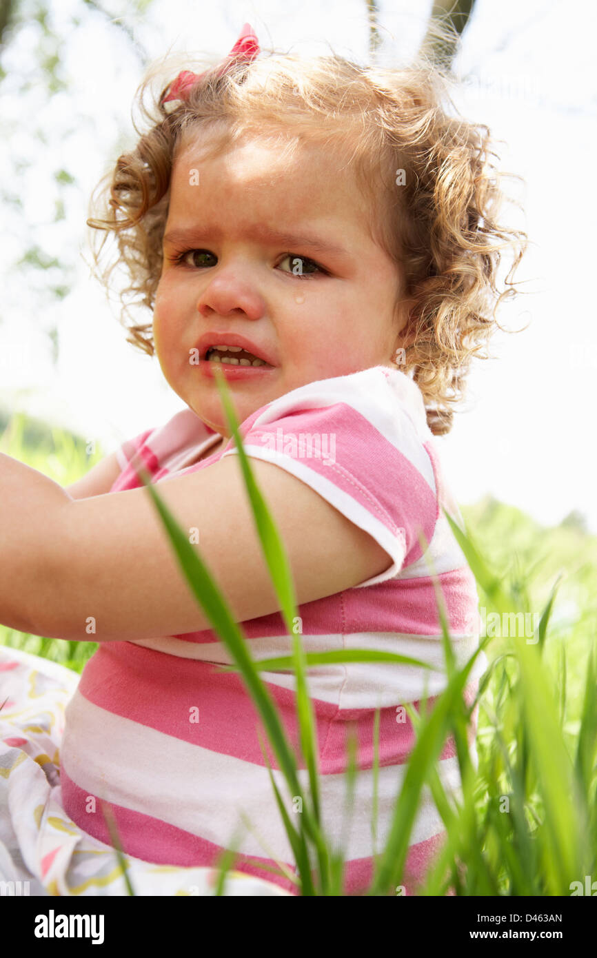Unhappy Young Girl Sitting In Summer Field Stock Photo