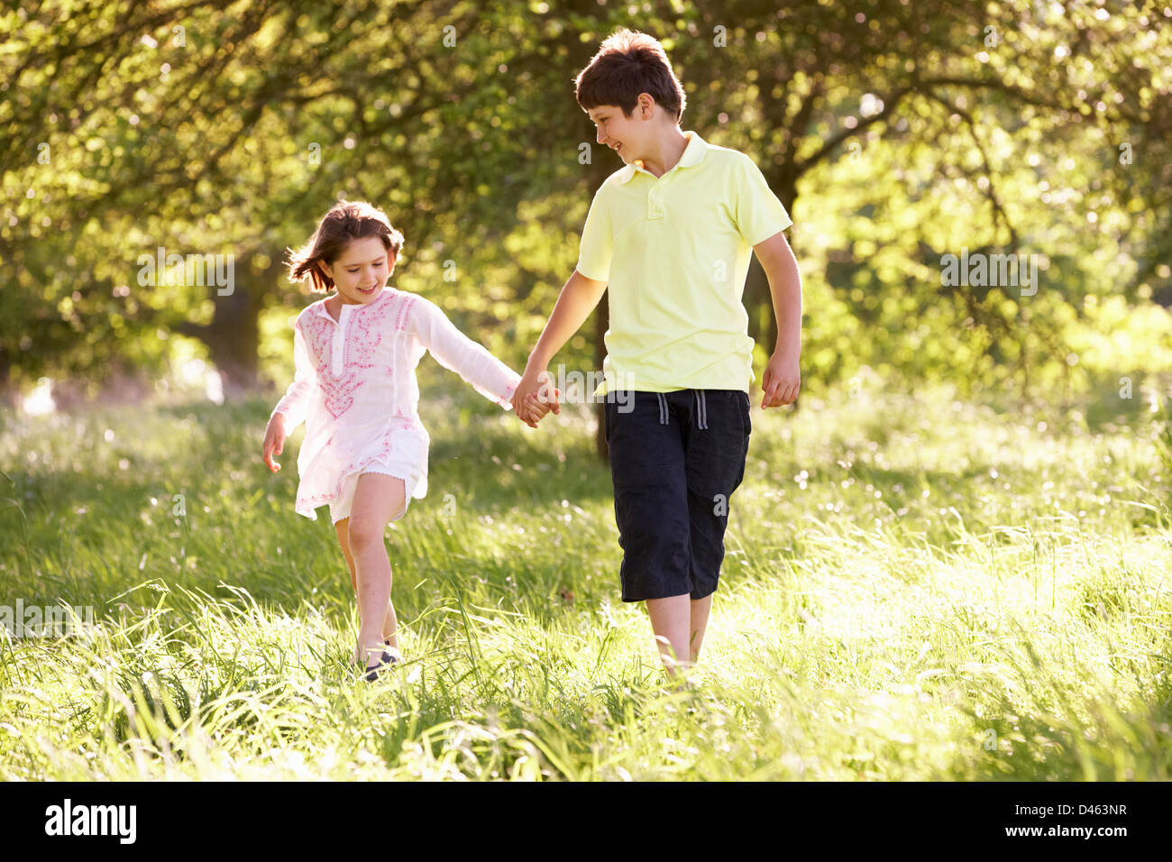 Boy And Girl Walking Through Summer Field Together Stock Photo