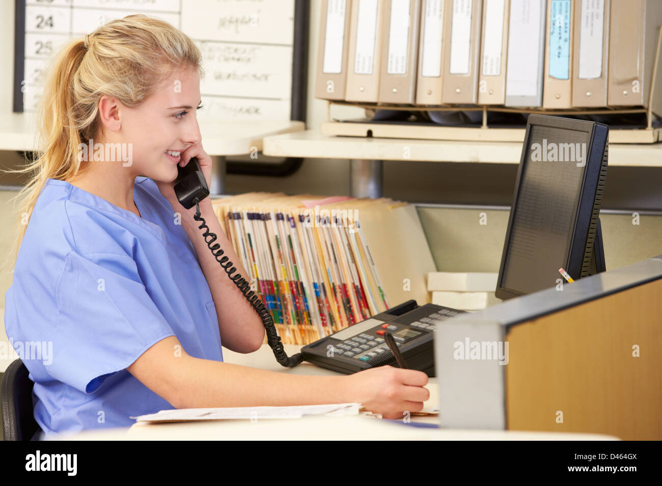 Nurse Making Phone Call At Nurses Station Stock Photo