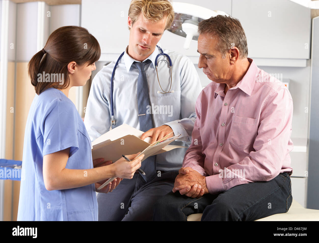 Male Patient Being Examined By Doctor And Intern Stock Photo