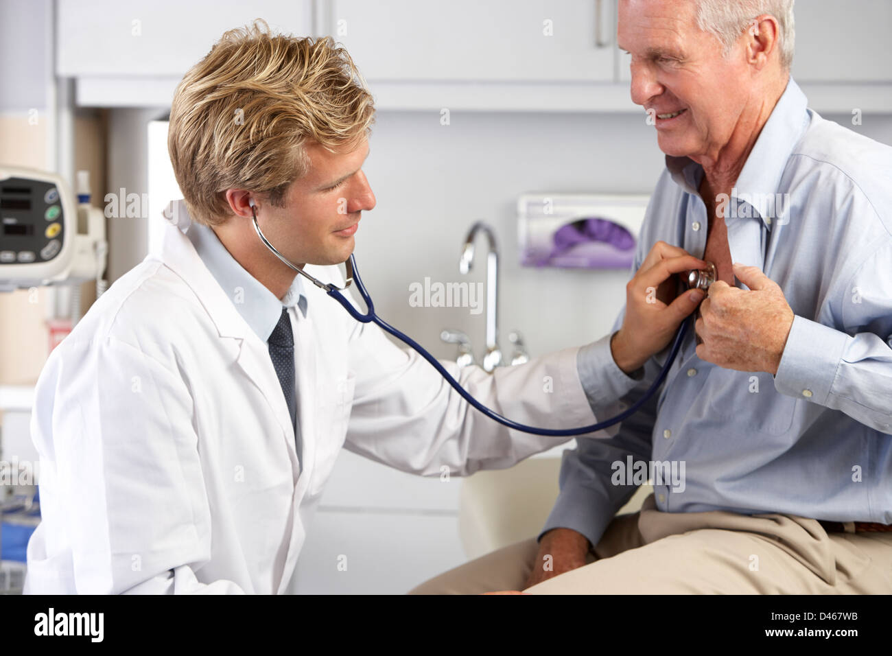 Doctor Listening To Male Patient's Chest Stock Photo