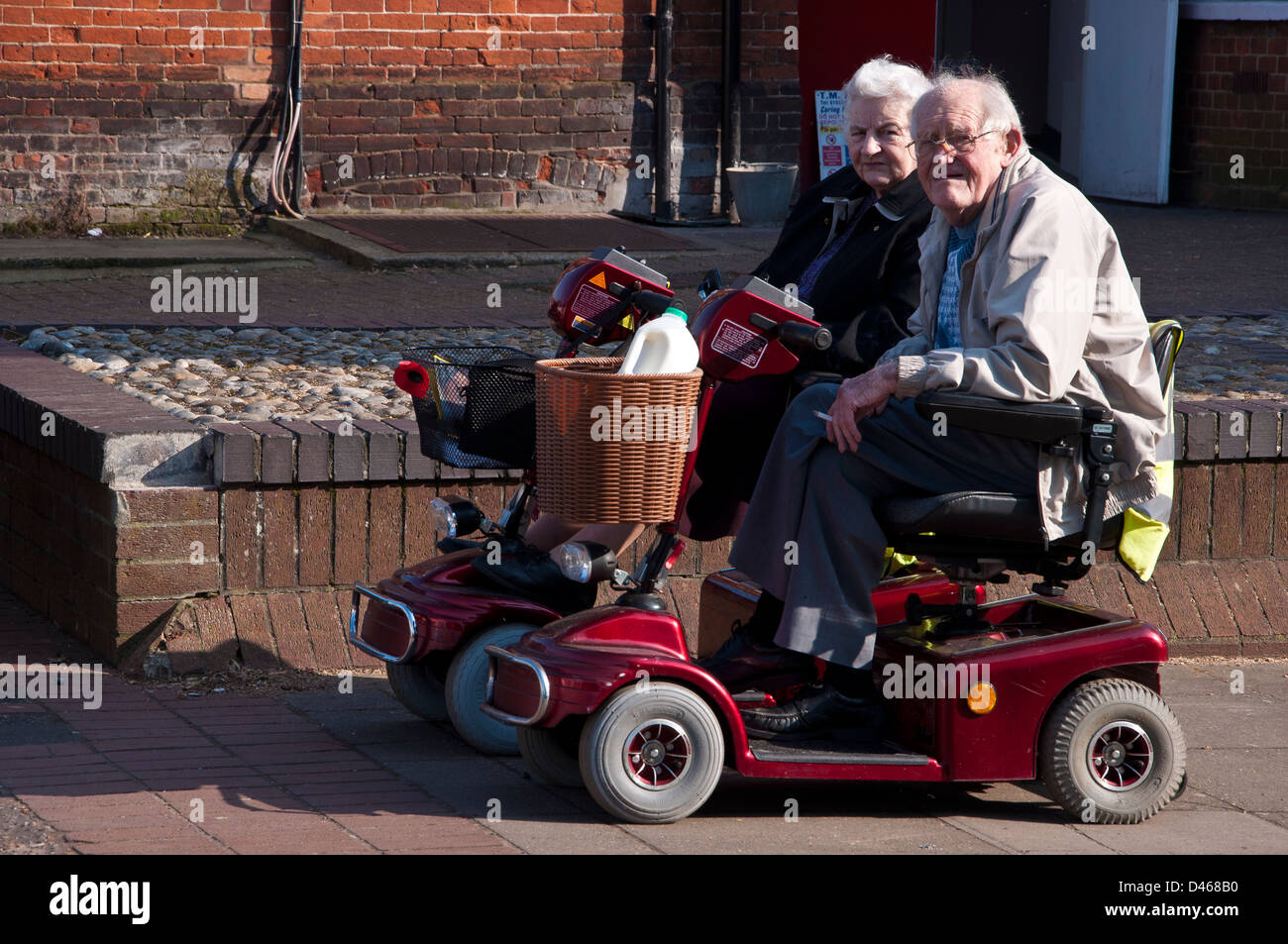 Senior couple pensioners sitting on mobility scooters Stock Photo