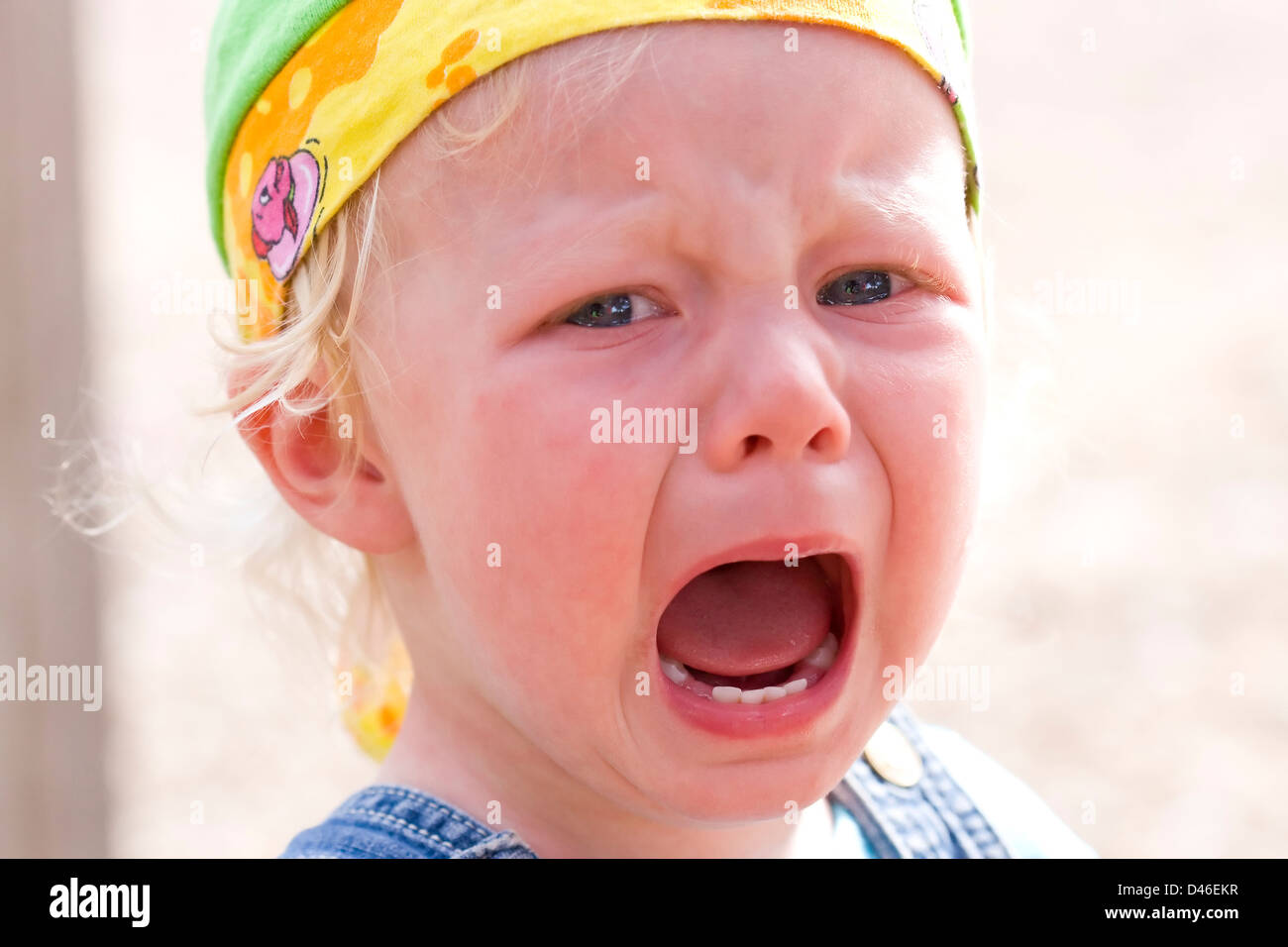 Close-up of a blond baby girl bawling furiously (focus on the left eye and the mouth). Stock Photo