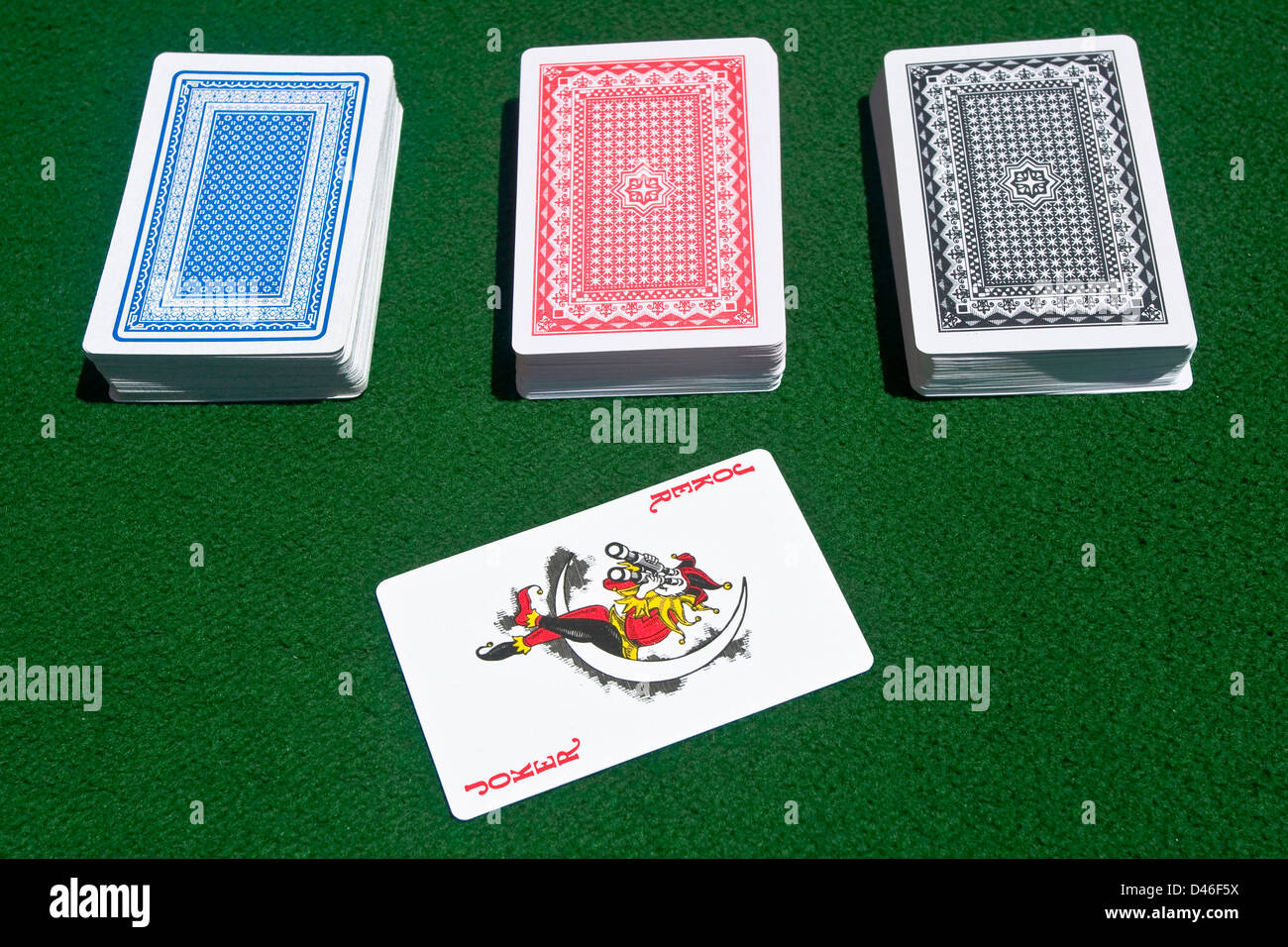 Shot of three complete different-color poker cards decks with a red joker. Stock Photo