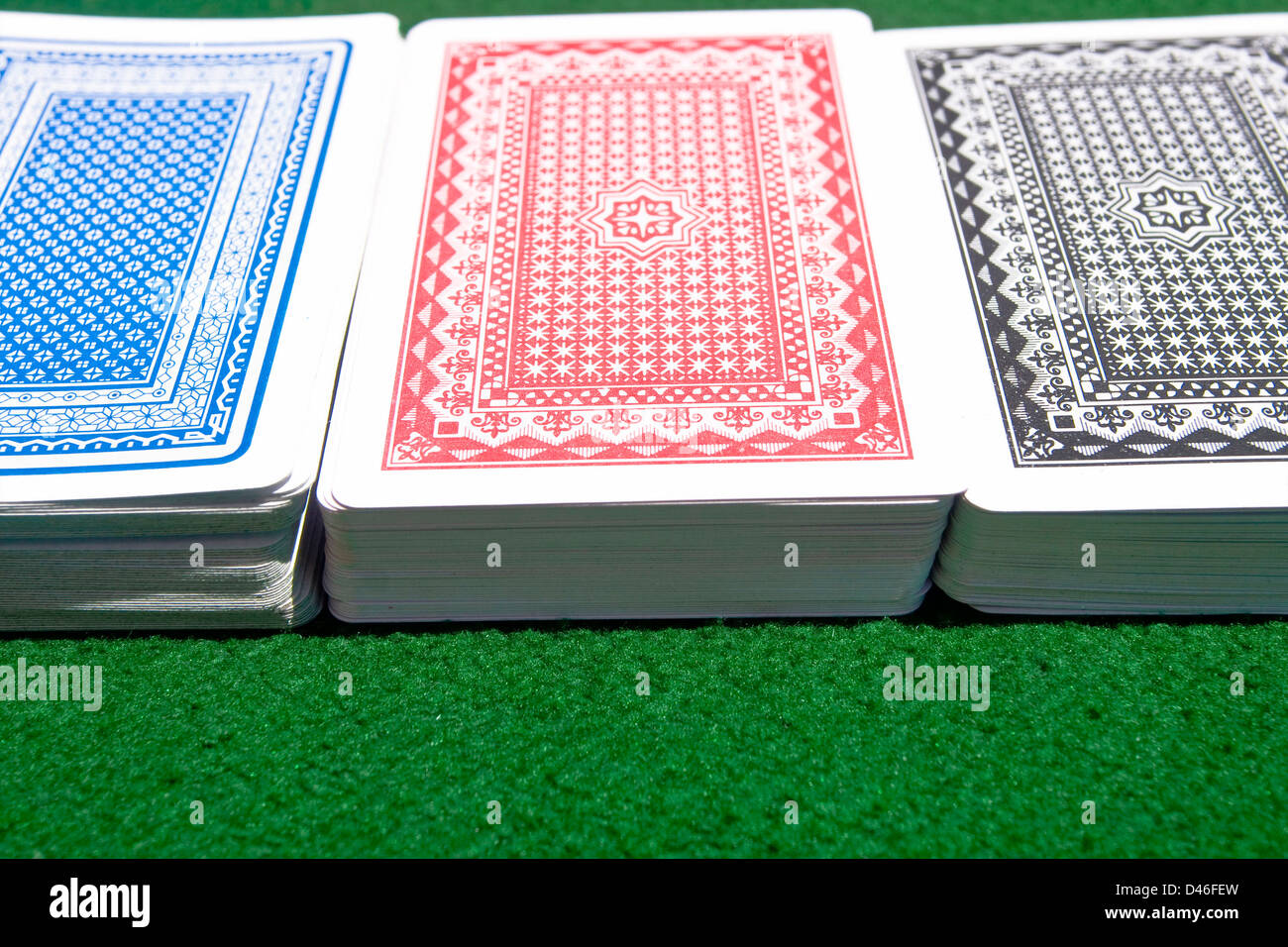 Three different-color decks of playing cards on the green playing table. Stock Photo