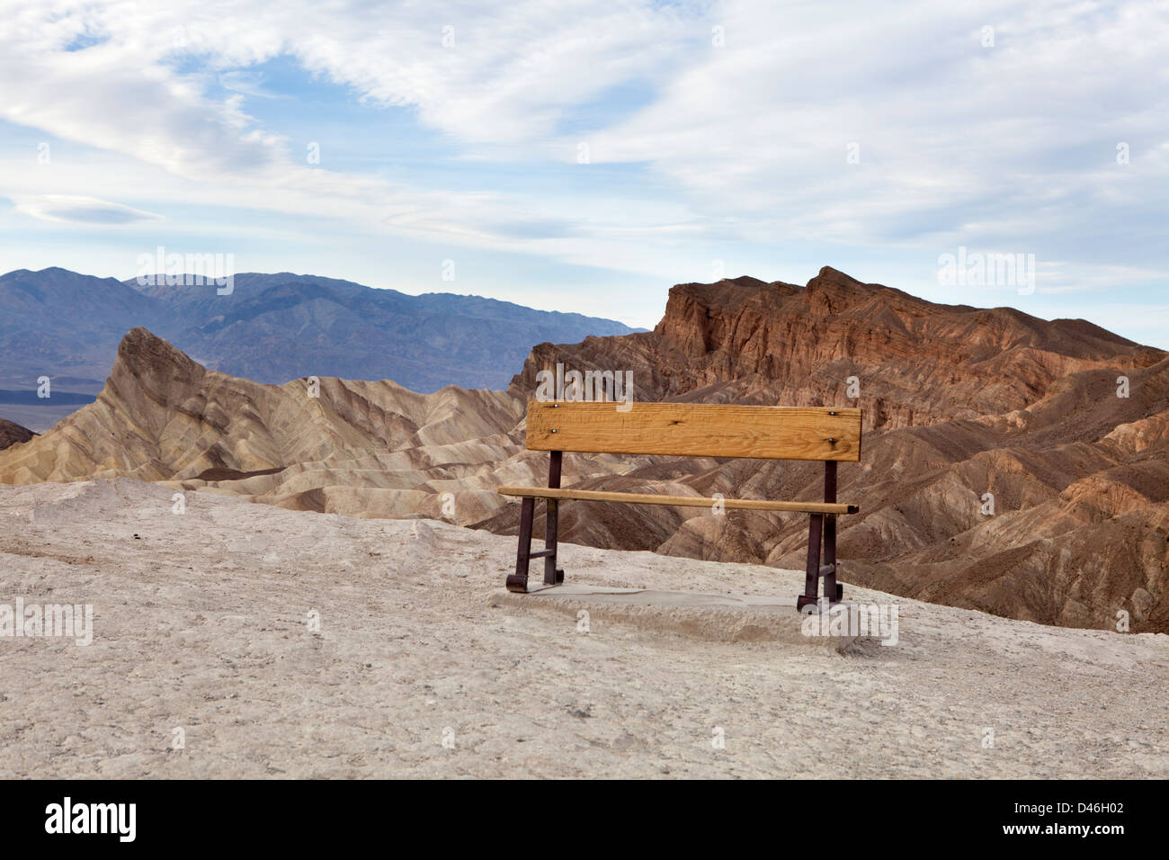 A bench in front of Badland formations at Zabriskie Point with blue sky and some clouds Stock Photo