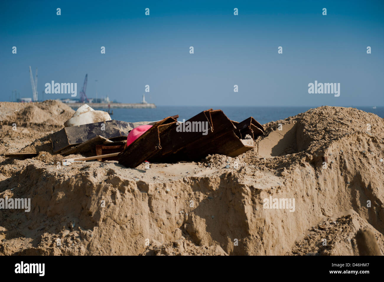 Metal piles and other materials laying in the sand ready to use on the repair of the seafront at Lowestoft. Stock Photo