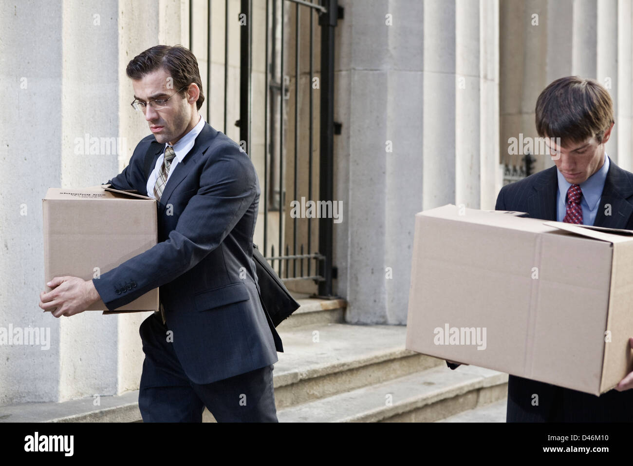 Two wall street men made redundant, carrying boxes of personal effects from work. Stock Photo