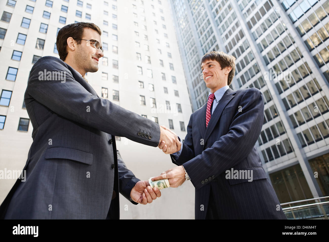 money changing hands under a handshake Stock Photo