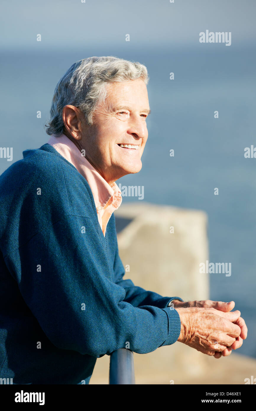 Senior Man Looking Over Railing At Sea Stock Photo