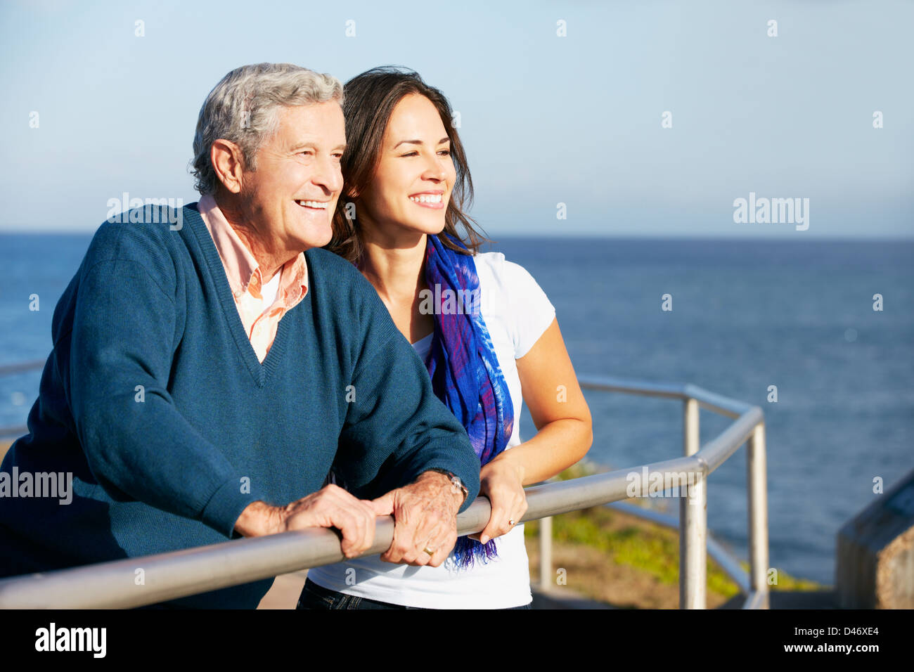 Senior Man With Adult Daughter Looking Over Railing At Sea Stock Photo