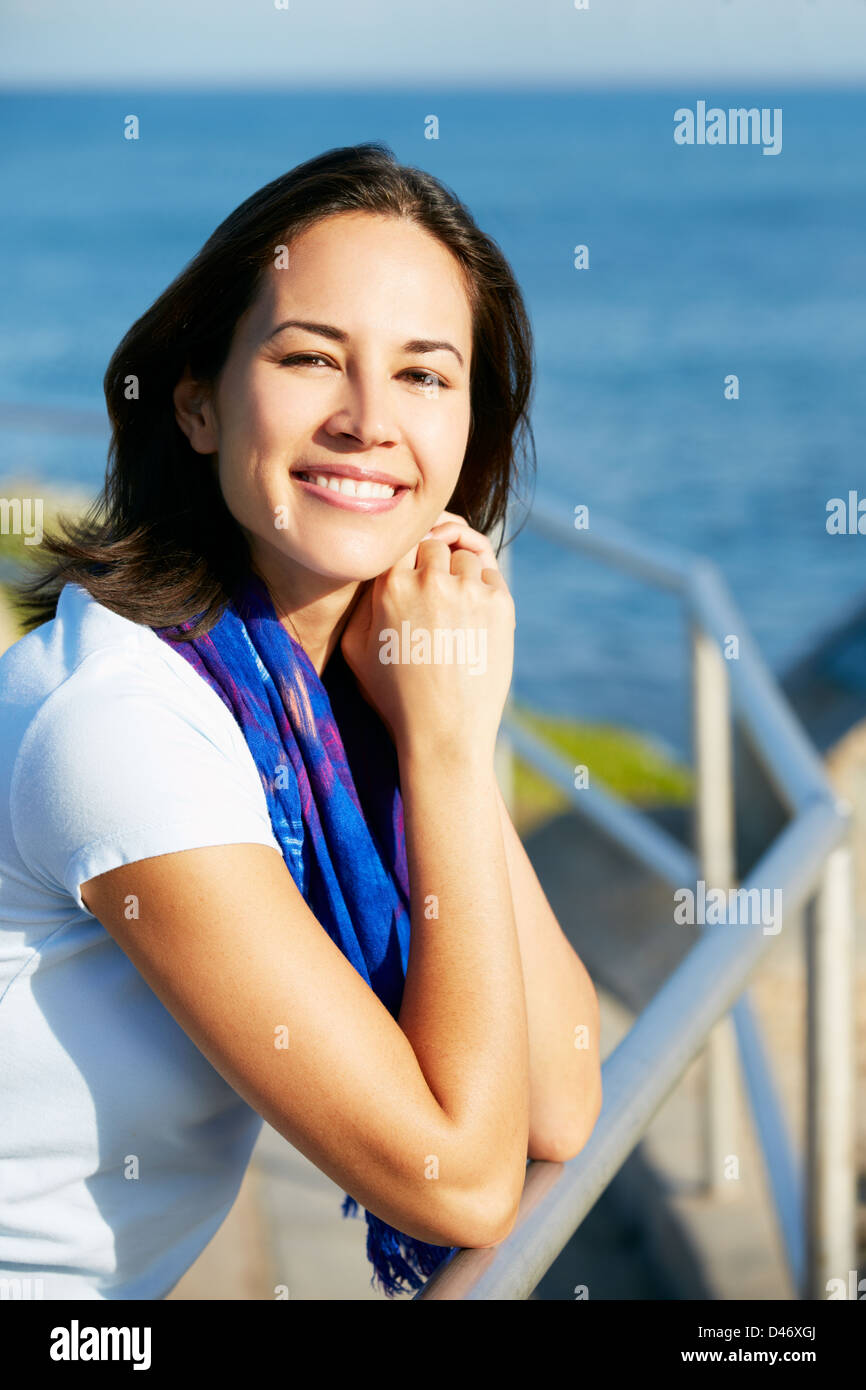 Hispanic Woman Looking Over Railing At Sea Stock Photo