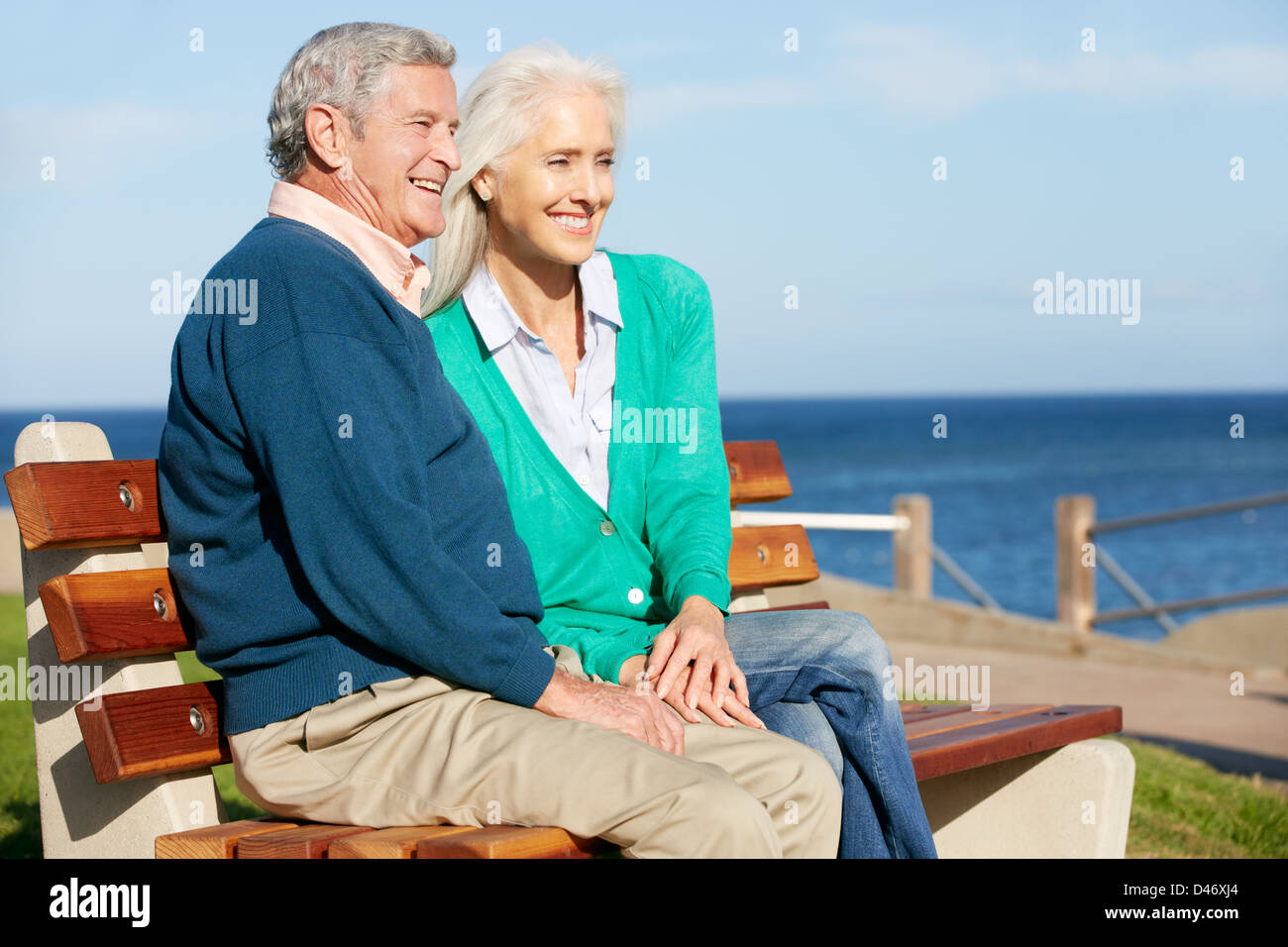 Senior Couple Sitting On Bench By Sea Together Stock Photo - Alamy