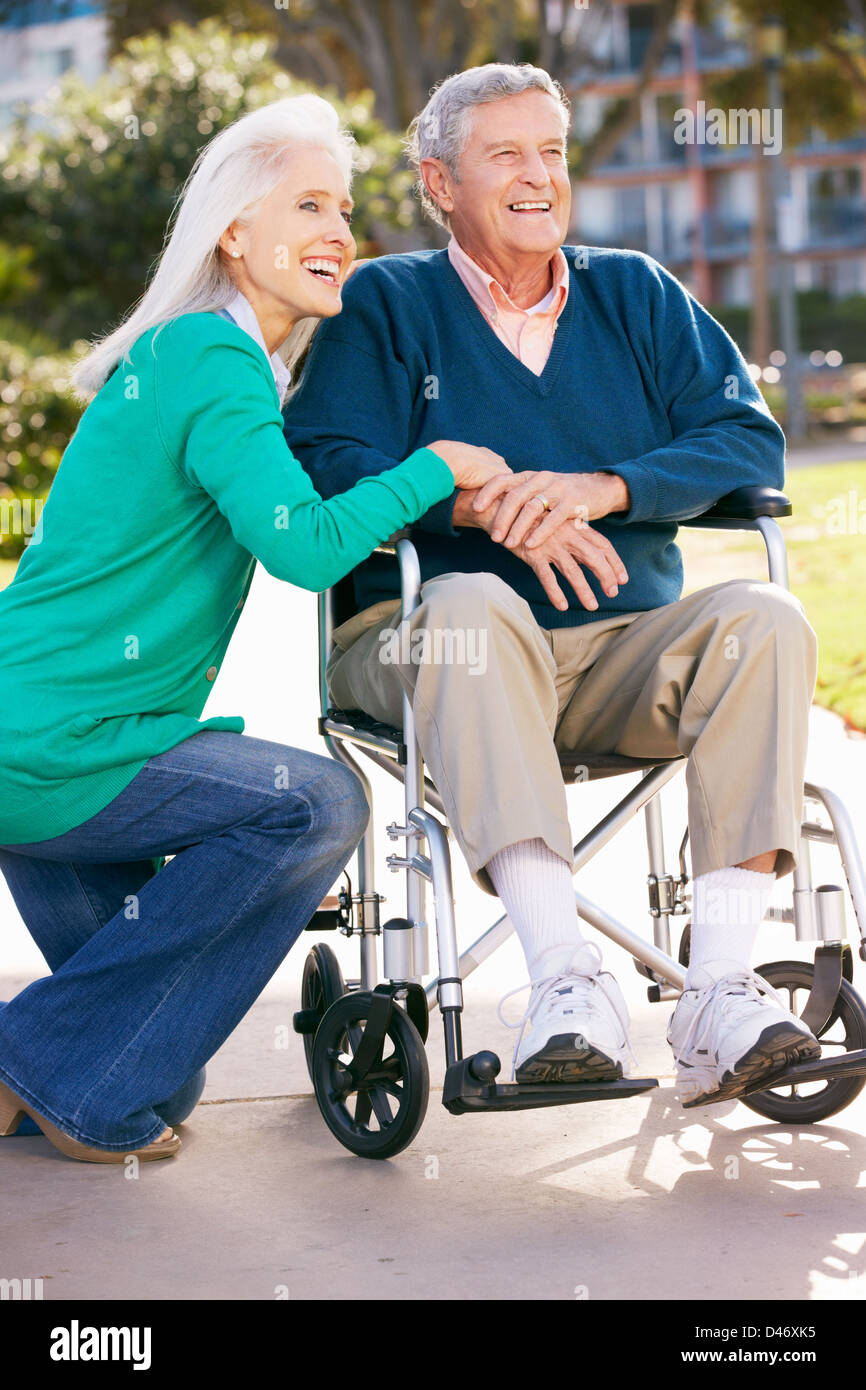 Senior Woman Pushing Husband In Wheelchair Stock Photo