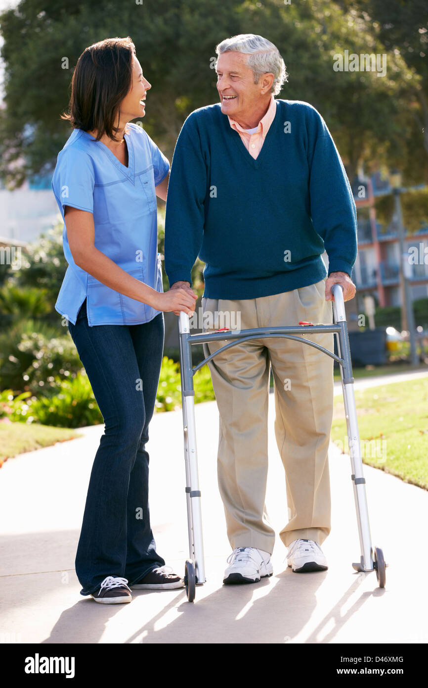 Carer Helping Senior Man With Walking Frame Stock Photo