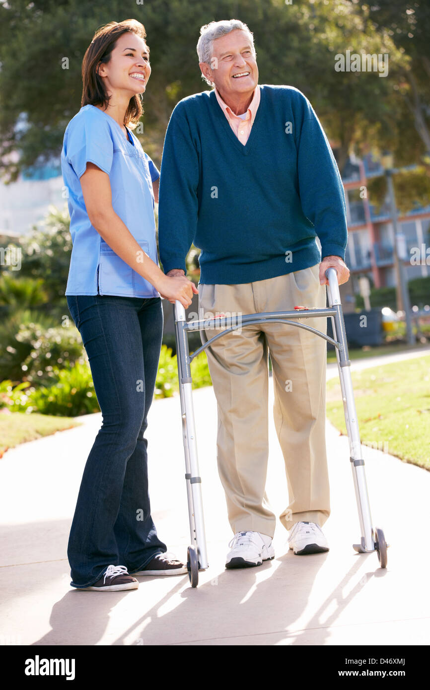 Carer Helping Senior Man With Walking Frame Stock Photo