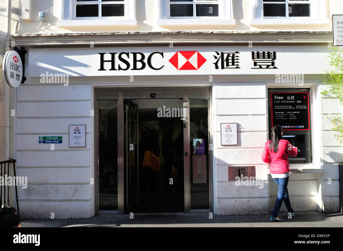 A young woman uses a cash mash at an HSBC branch in China Town, central London, UK. Stock Photo