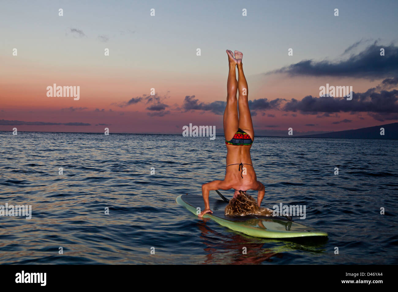 Surf instructor Tara Angioletti does a sunset head stand on her stand