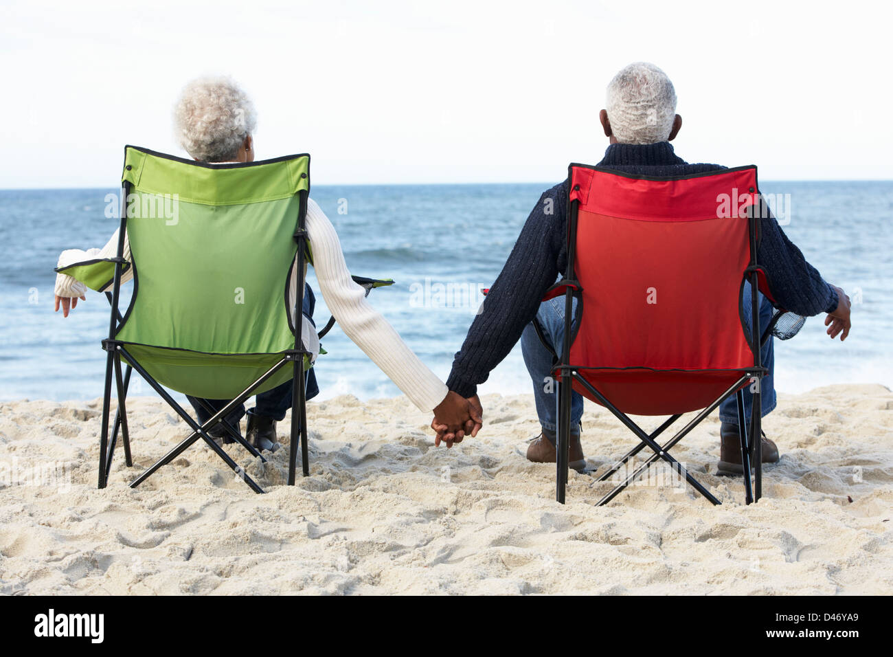 Senior Couple Sitting On Beach In Deckchairs Stock Photo - Alamy