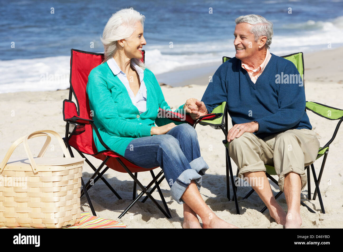 Senior Couple Sitting On Beach In Deckchairs Having Picnic Stock Photo ...
