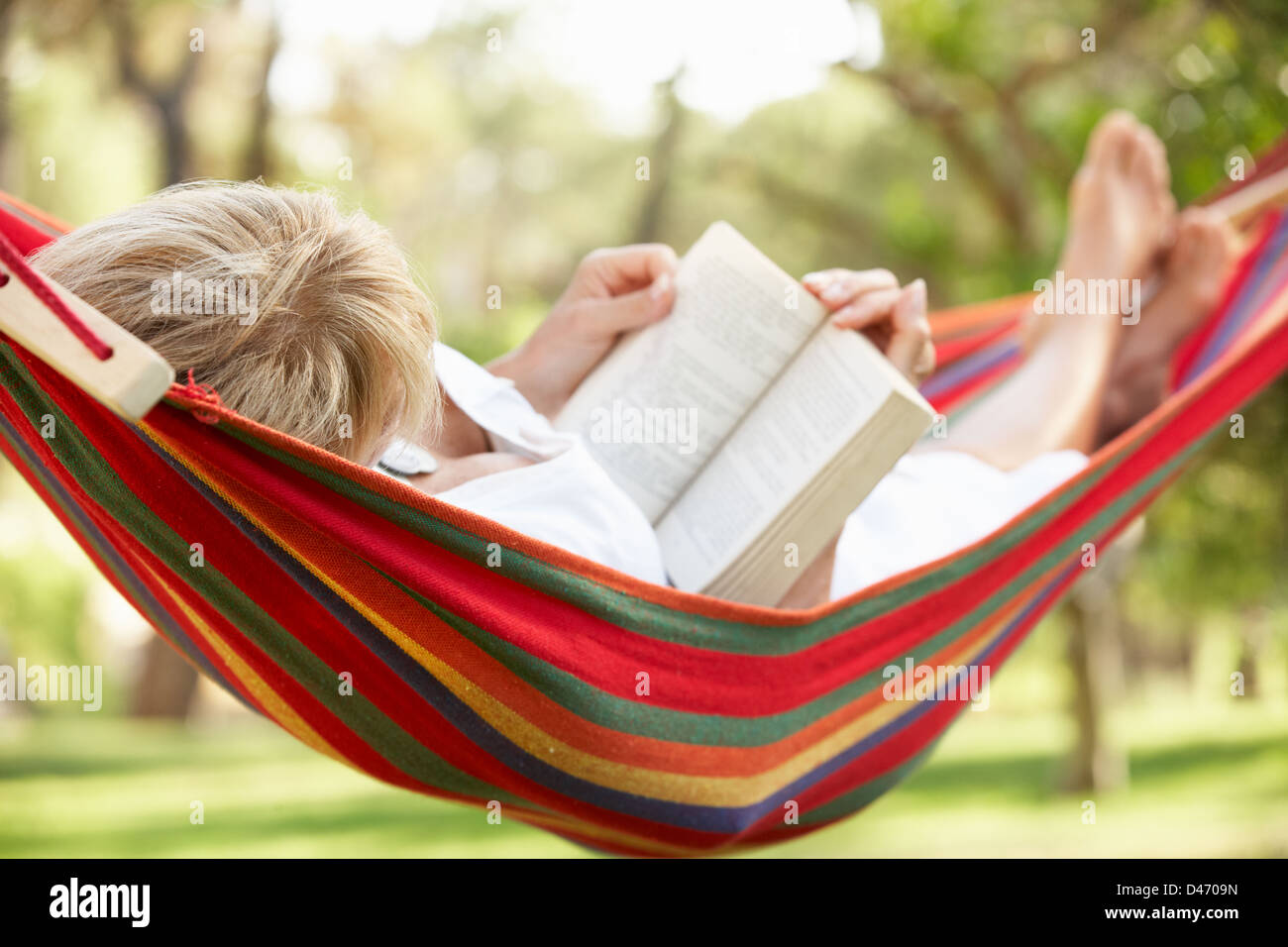 Senior Woman Relaxing In Hammock With Book Stock Photo - Alamy