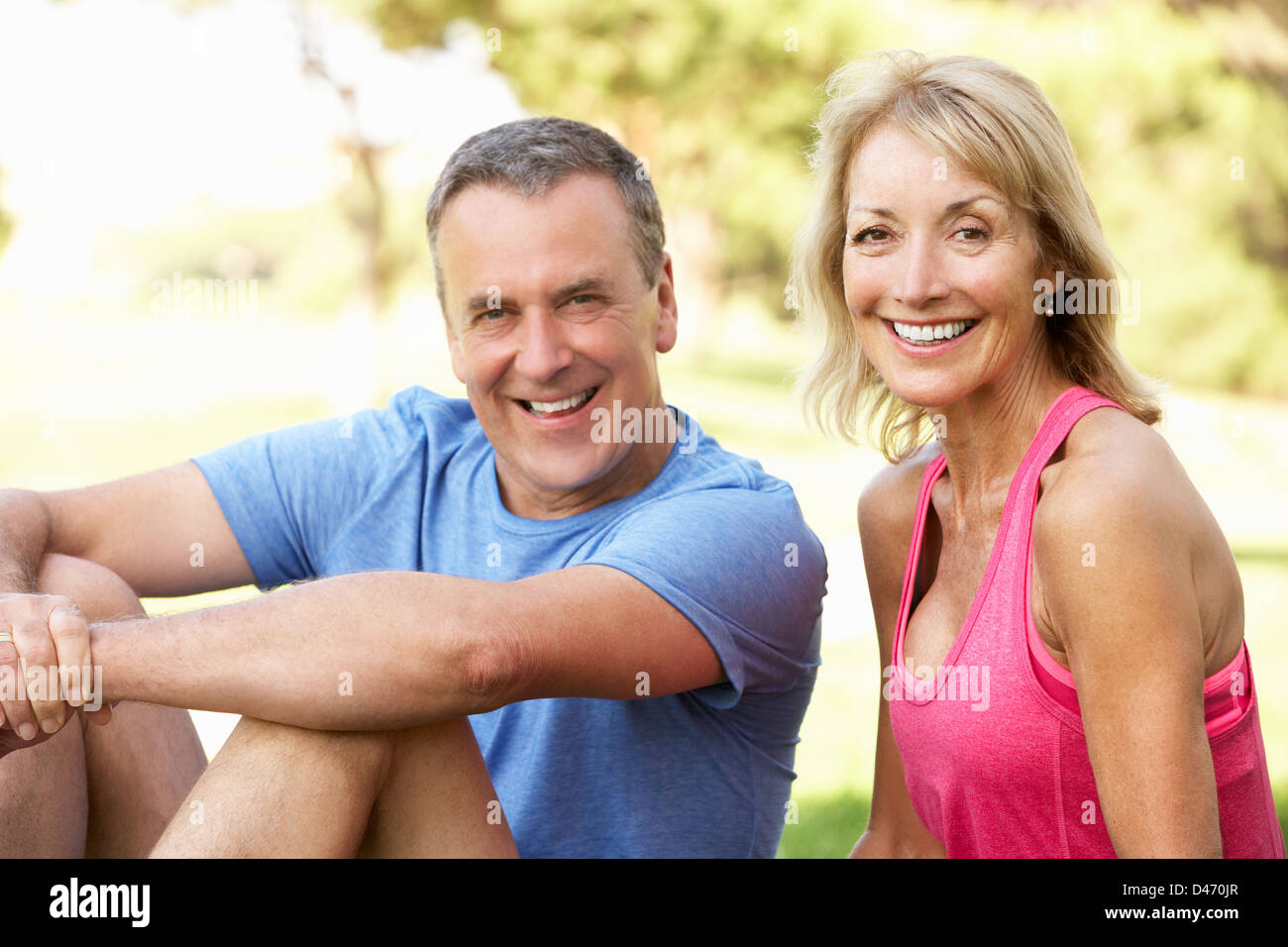 Senior Couple Resting After Exercising In Park Stock Photo