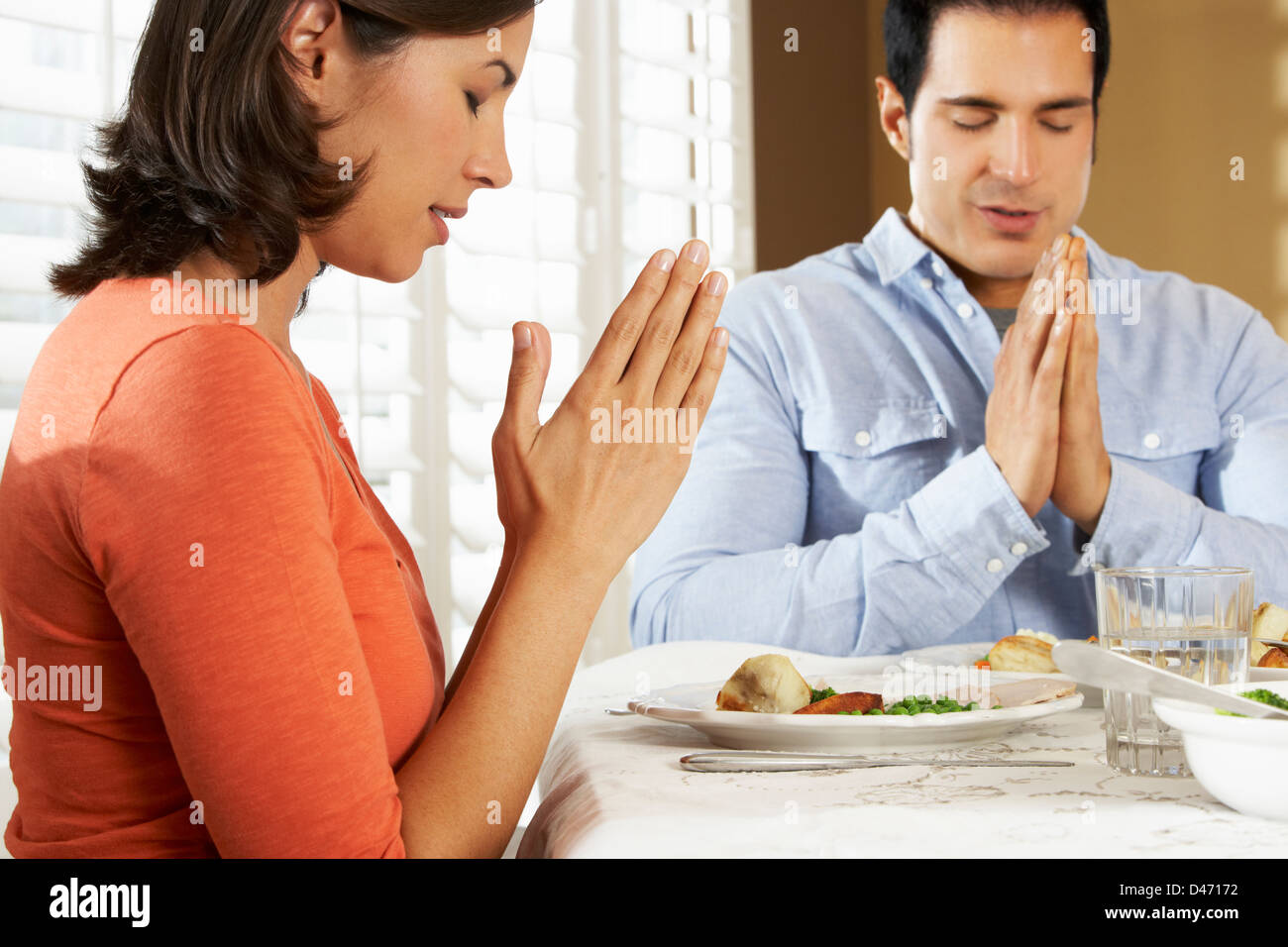 Couple Saying Grace Before Meal At Home Stock Photo