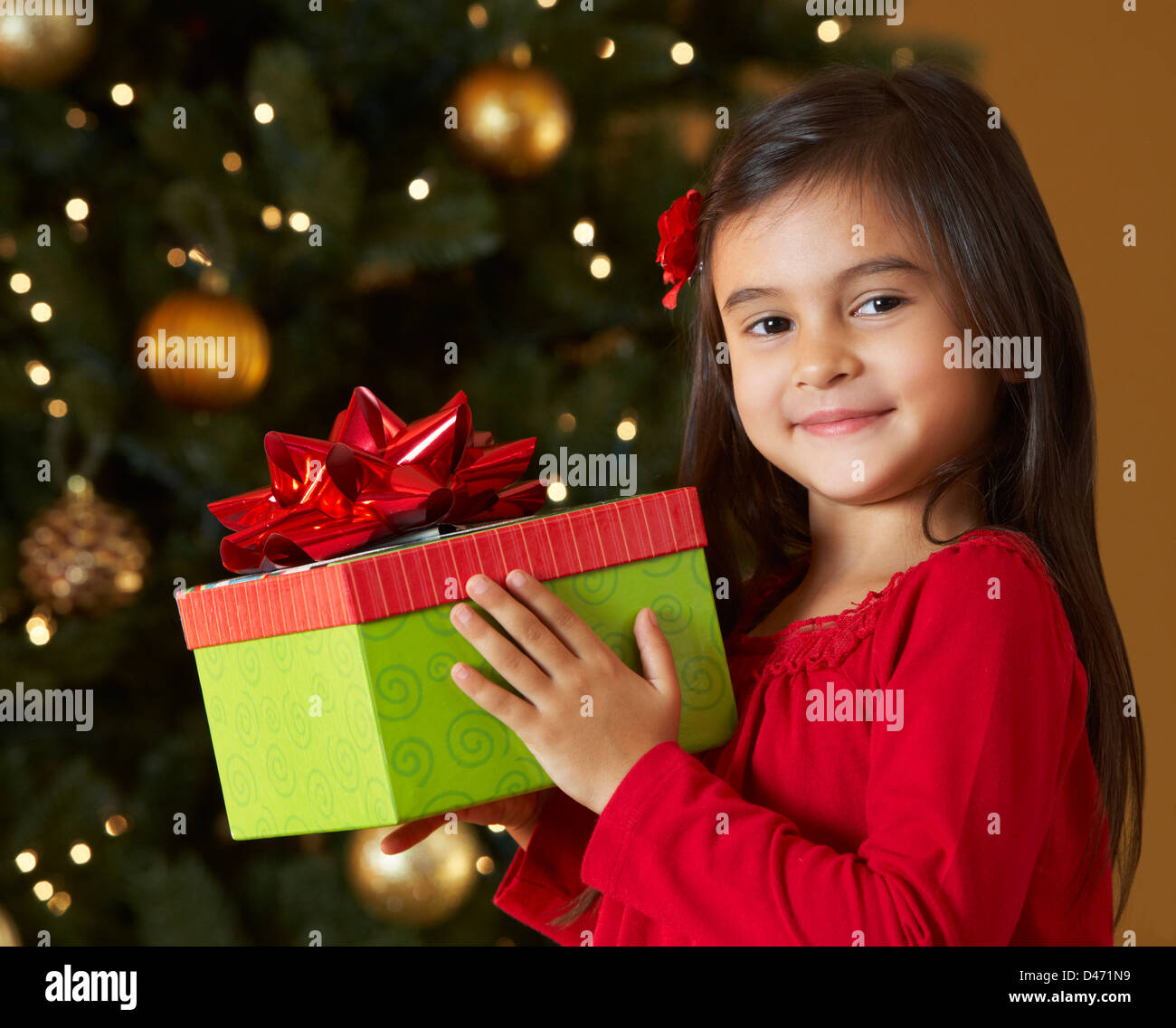 Girl Holding Christmas Present In Front Of Tree Stock Photo - Alamy