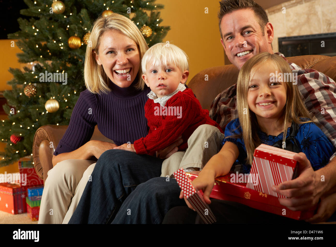 Family Opening Presents In Front Of Christmas Tree Stock Photo Alamy