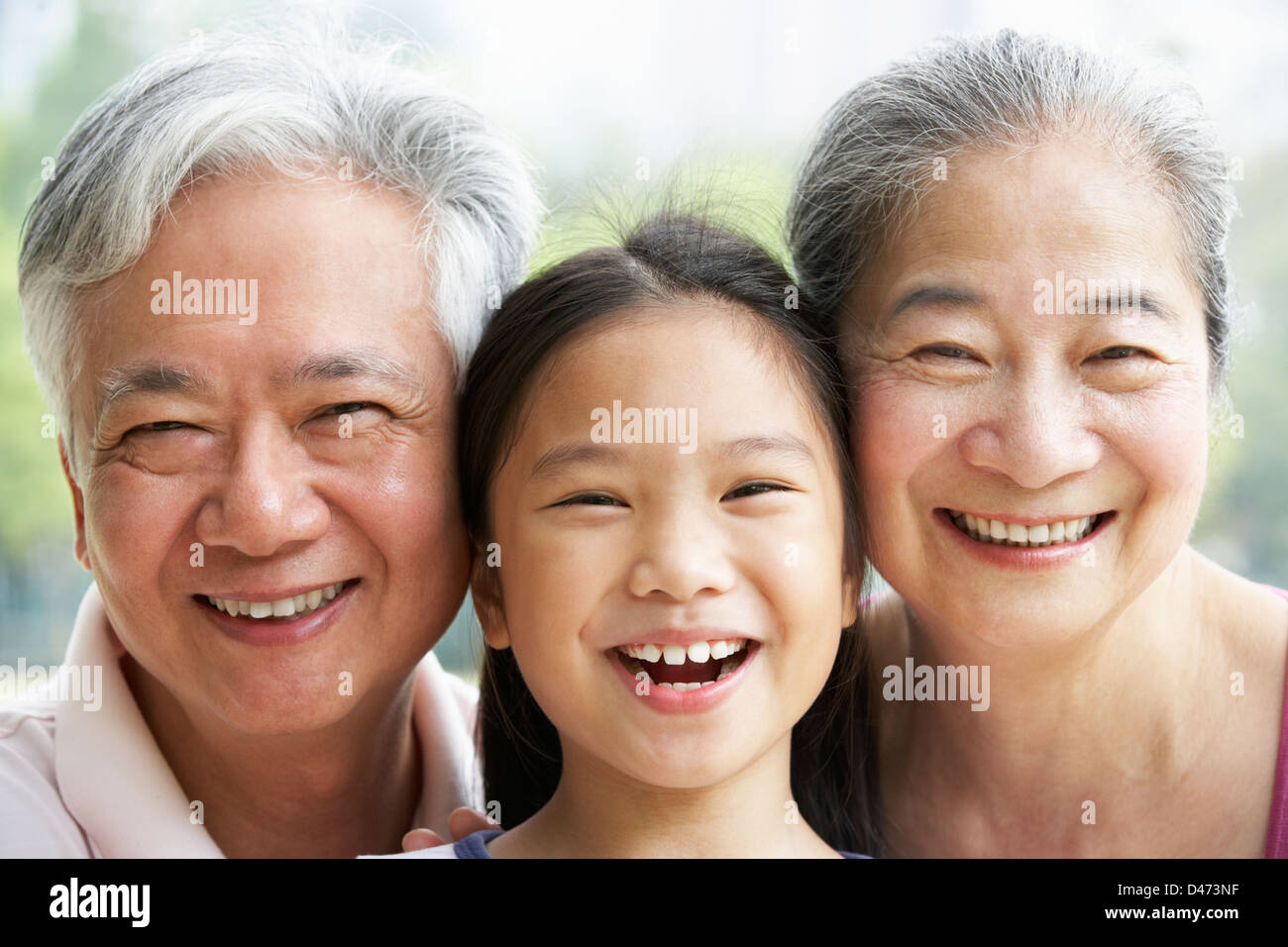 Head And Shoulders Portrait Of Chinese Grandparents With Granddaughter Ride Stock Photo