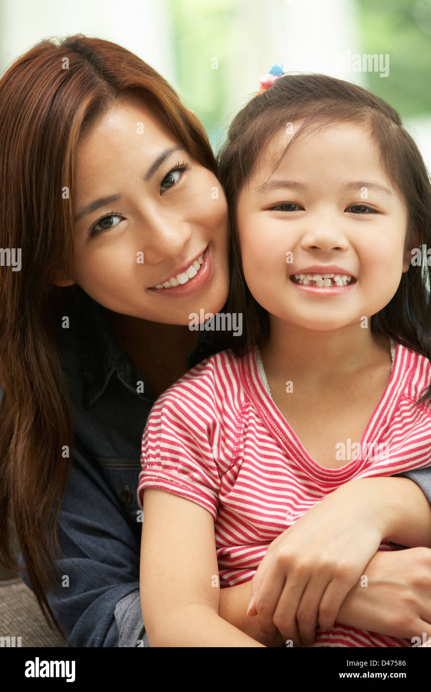 Chinese Mother And Daughter Sitting On Sofa At Home Together Stock Photo