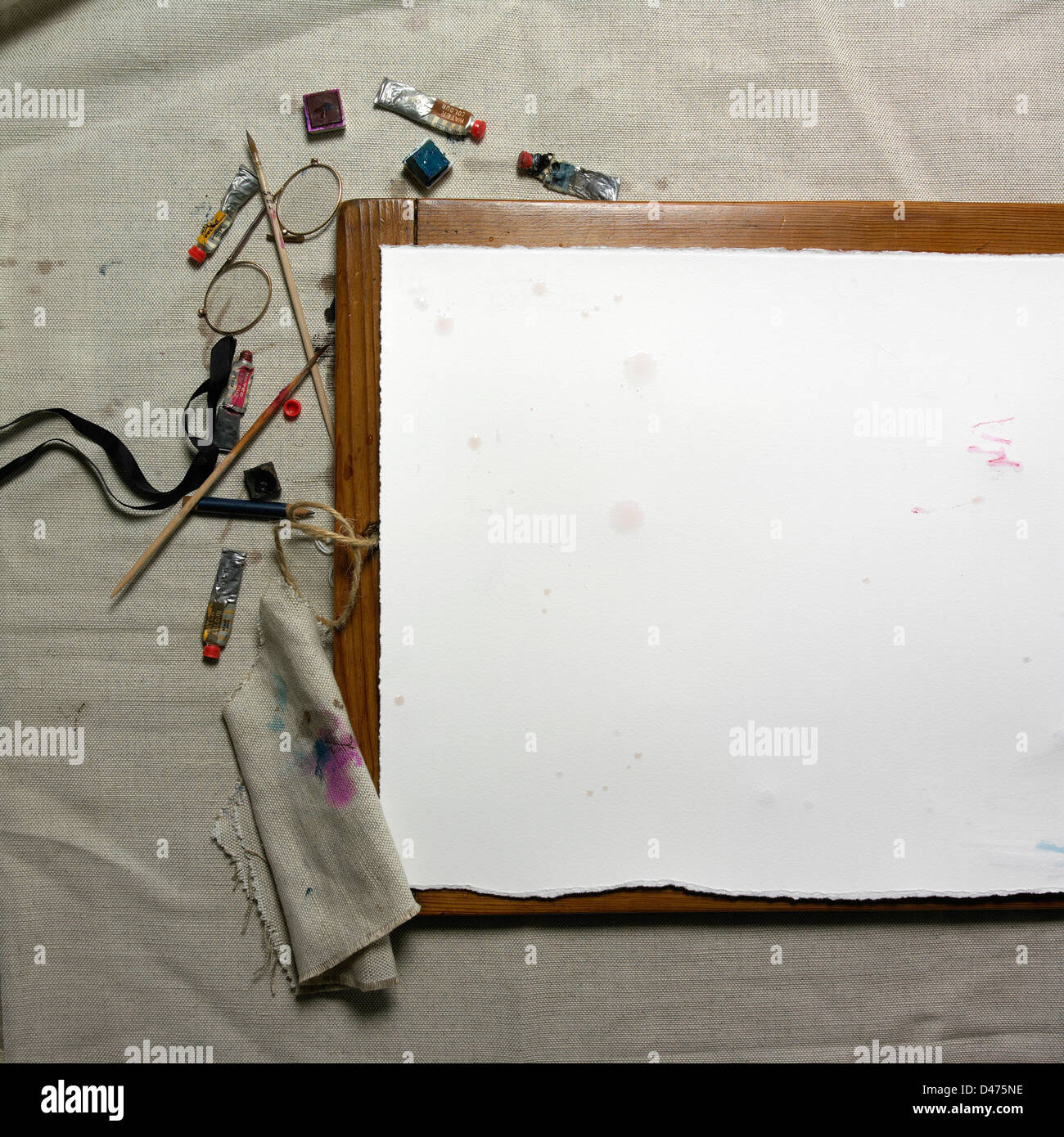 Overhead shot of artists board with watercolour paper on a  grey fabric background Stock Photo