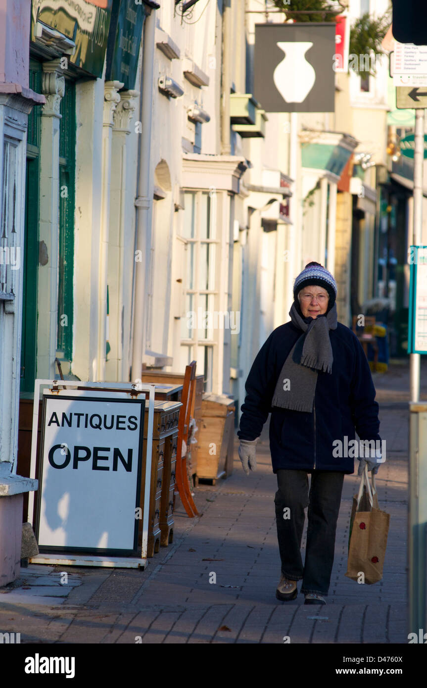 Lady shopping outside an antiques shop in the winter on the high street. Honiton, Devon, UK Stock Photo
