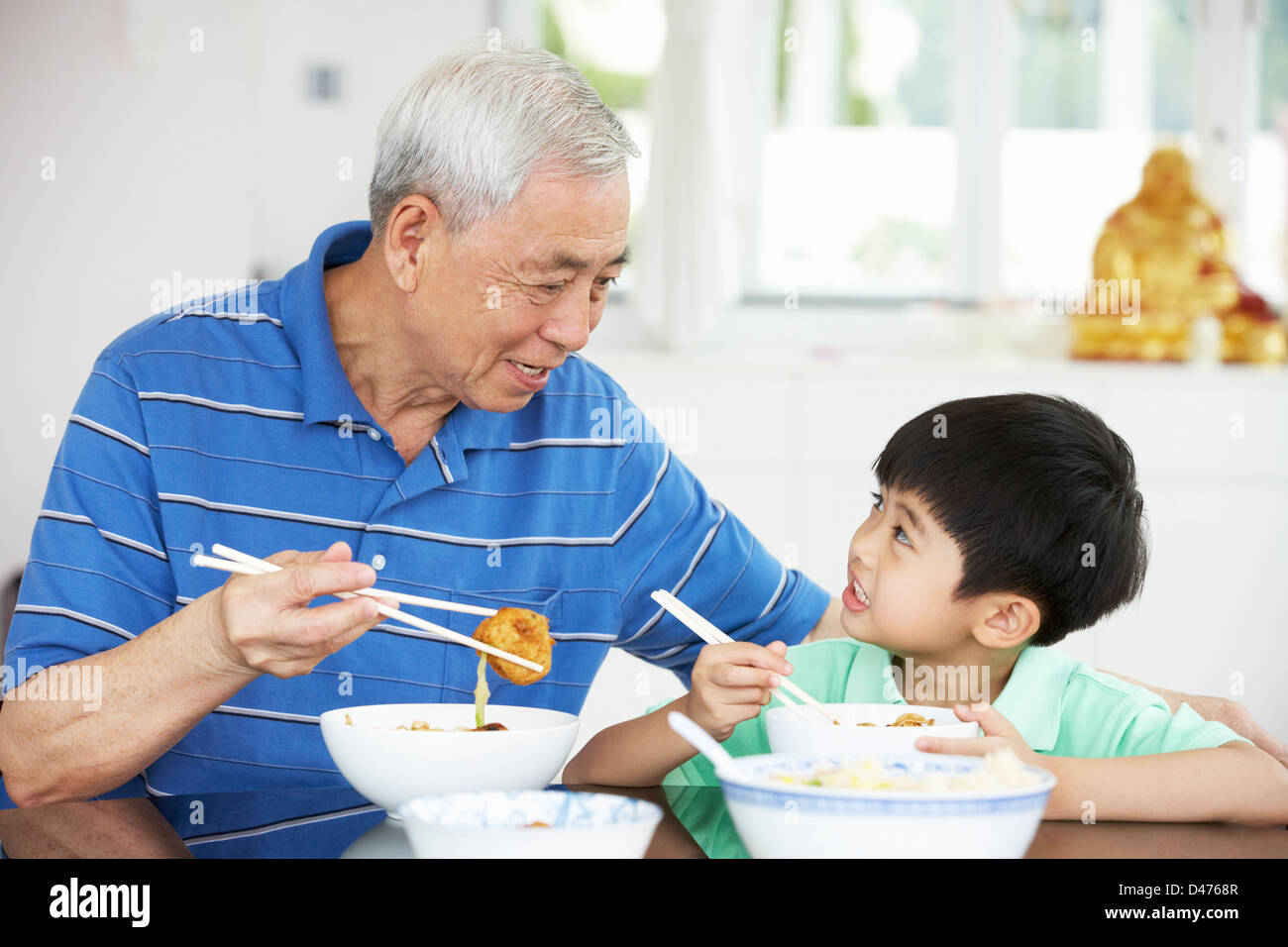 Portrait Of Chinese Grandfather And Grandson Eating Meal Together Stock