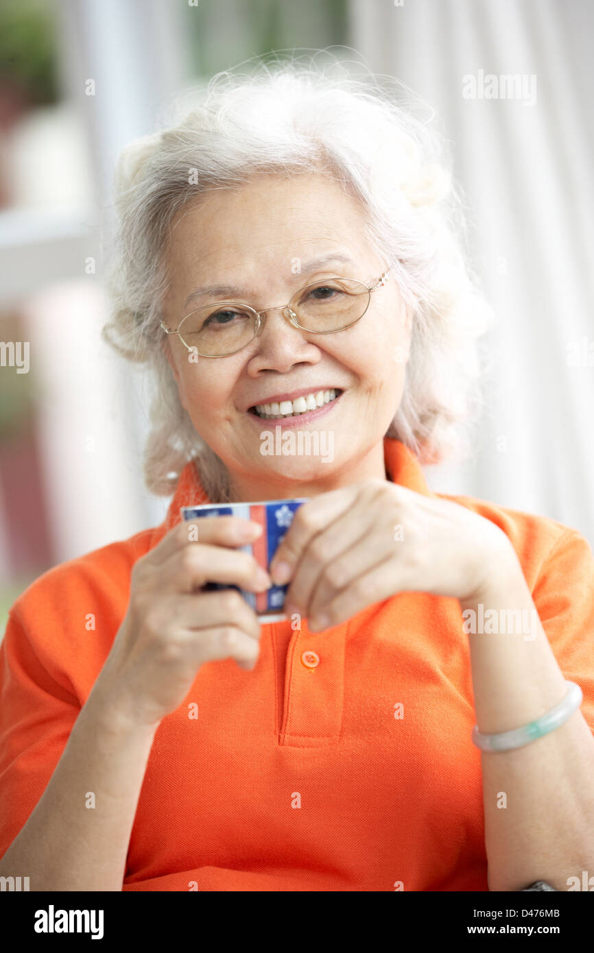 Senior Chinese Woman Drinking Tea On Sofa At Home Stock Photo