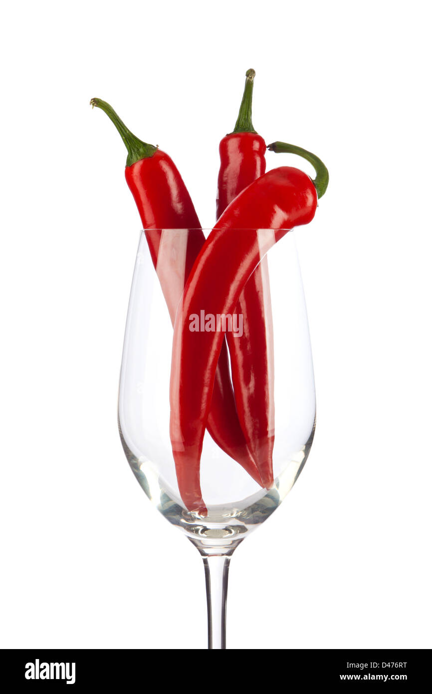 Three red chili peppers in a wine glass, isolated on white background