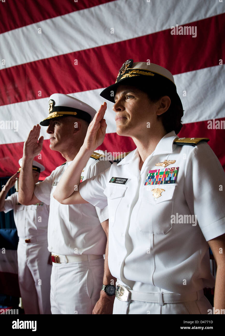 Admiral salutes with the official party as her flag is hauled up during a change of command ceremony Stock Photo