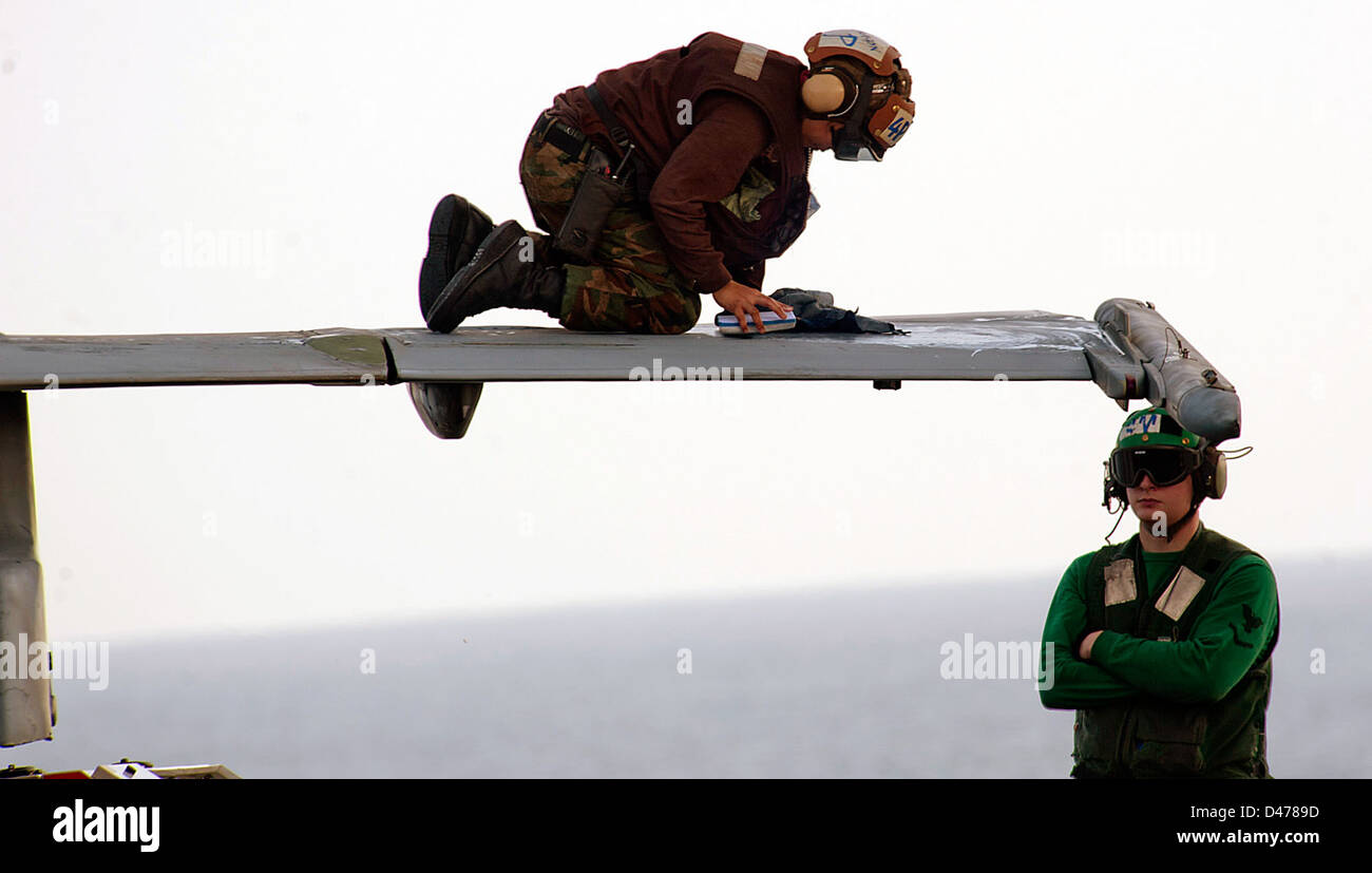 A Sailor wipes down the wing of an F/A-18C Hornet from the Golden Dragons of Strike Fighter Squadron (VFA) 192. Stock Photo