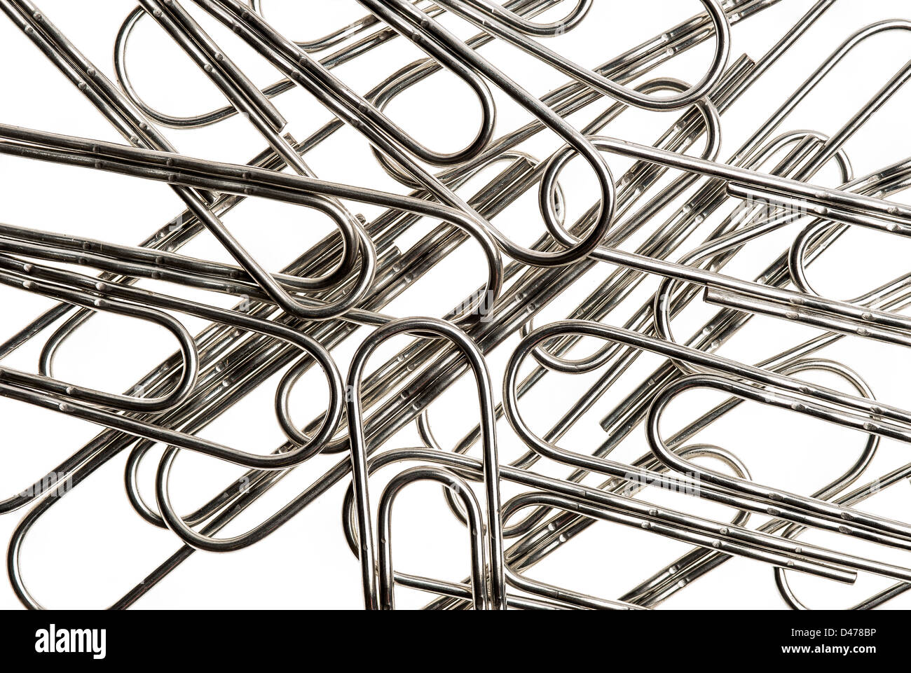 Small pile of large paper clips. Silver design on white background. Stock Photo