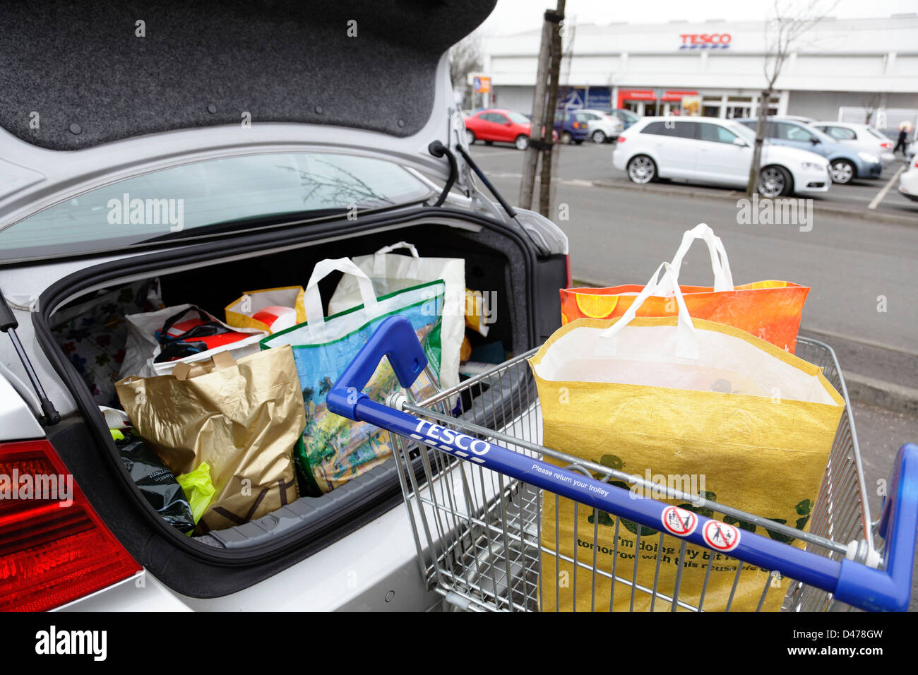 Shopping bags in a Tesco shopping trolley and car boot in a Tesco car park, Scotland, UK Stock Photo