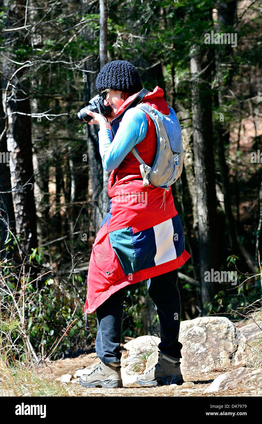 A woman hiker stopping on a trail to take a photo. Stock Photo