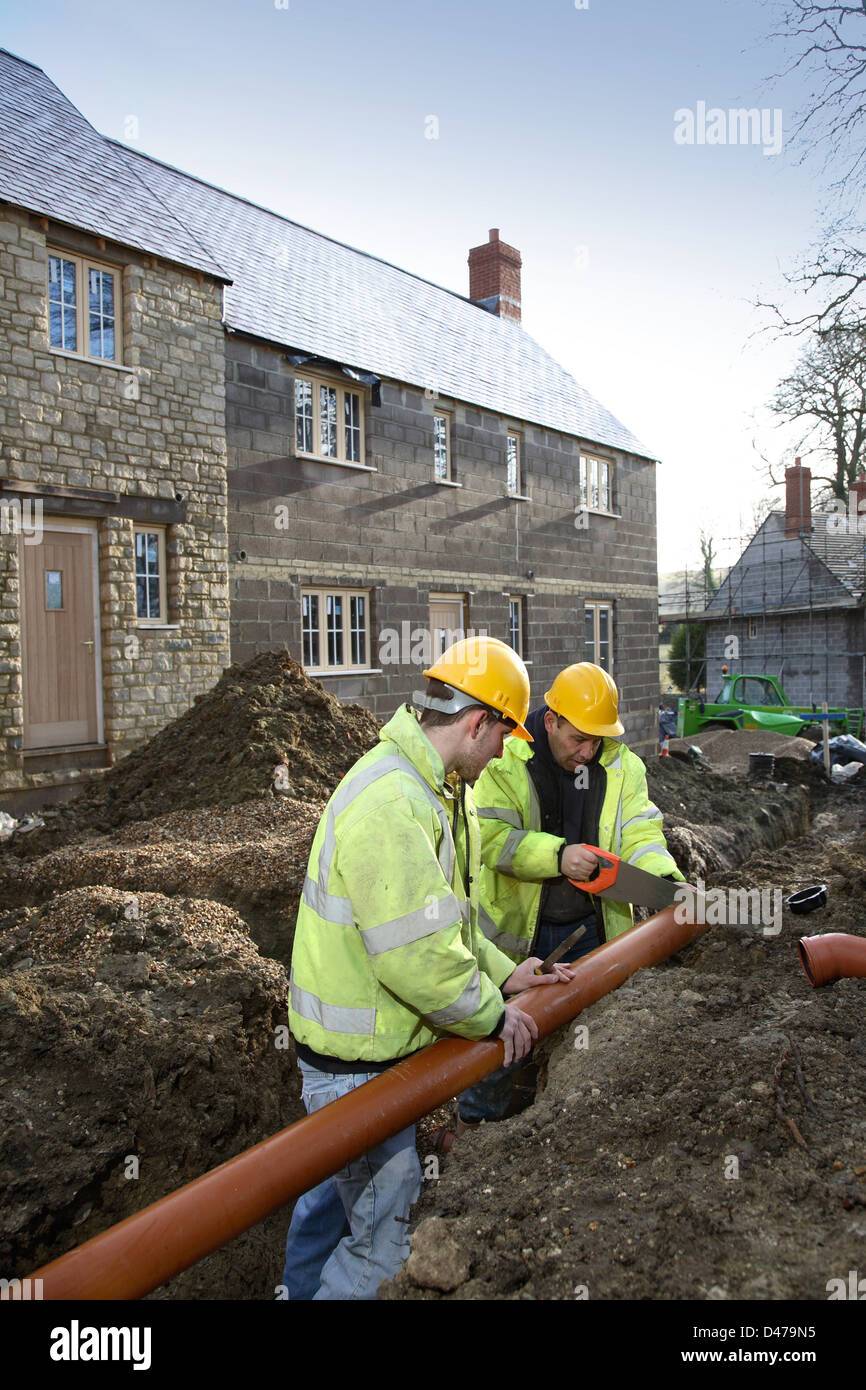 Workmen installing drainage pipes on a traditional housing development in Dorset, UK Stock Photo
