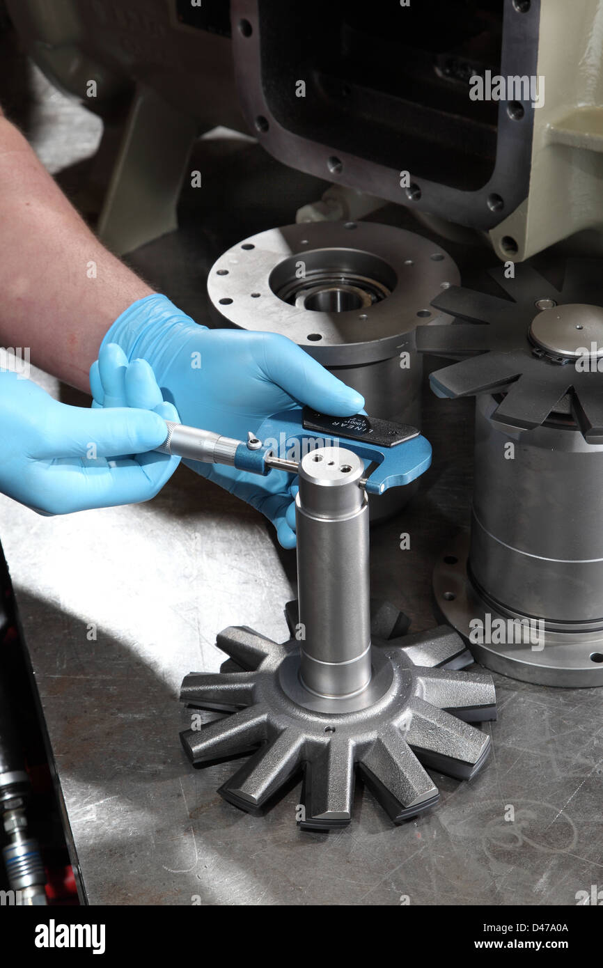An engineer uses a micrometer to measure the diameter of a compressor component Stock Photo