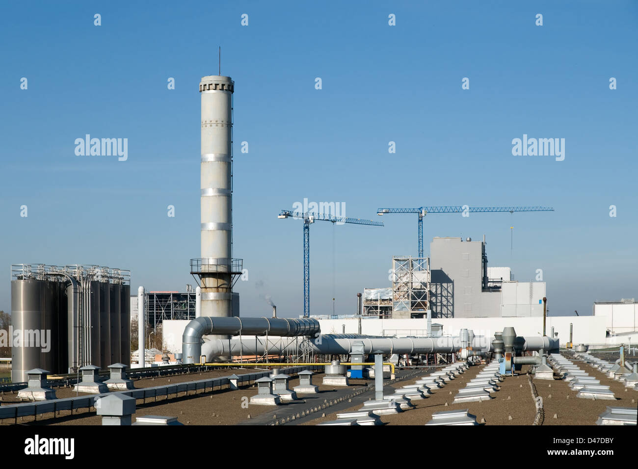 Factory pipes and cranes on a background of the blue sky Stock Photo ...