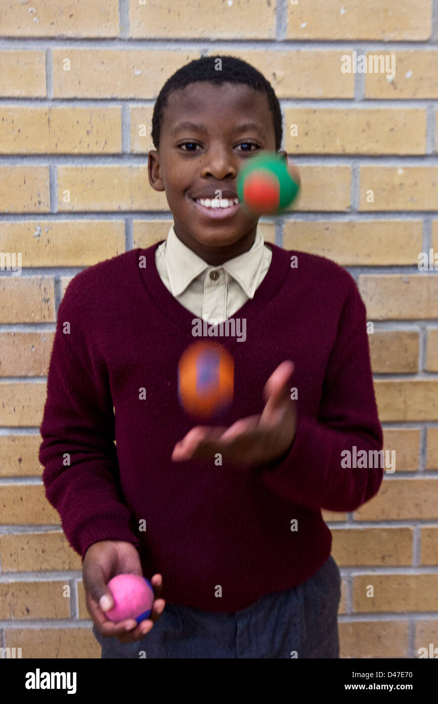 African school boy juggling balls as part of a circus class in hall of