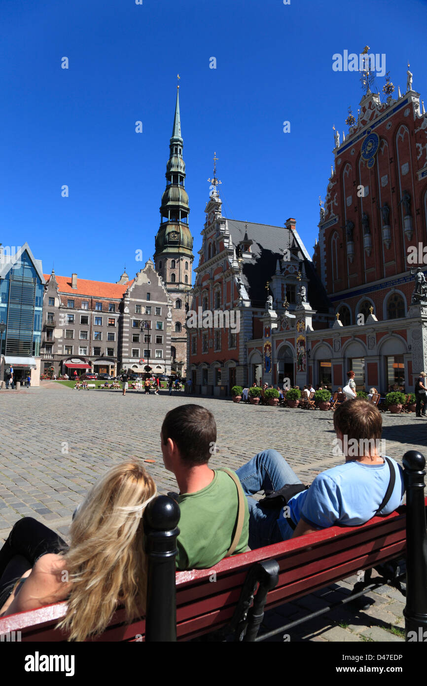 Tourists sitting on Town Hall Square (Ratslaukums), View to Blackheads House and tower of St.Peter Church Stock Photo