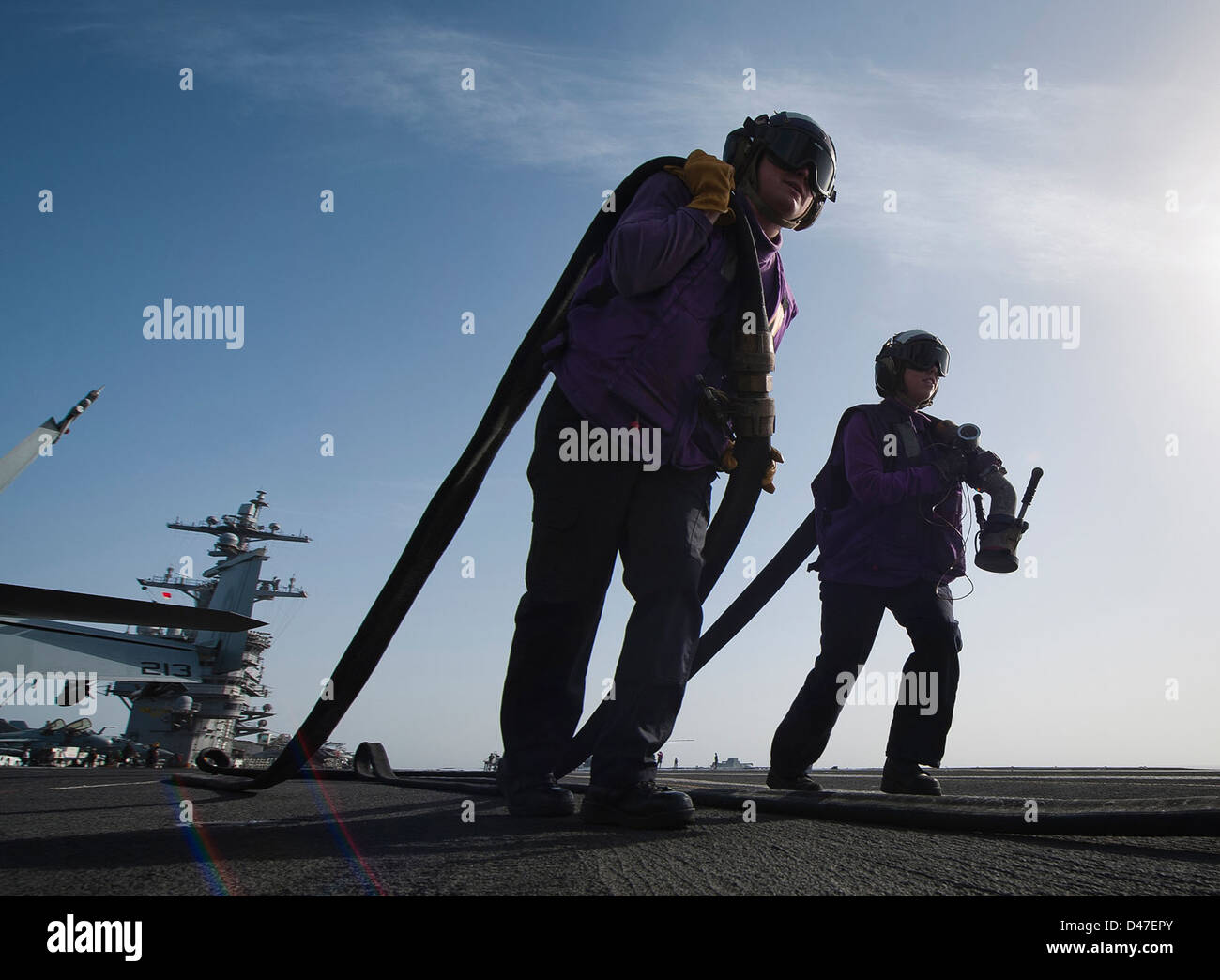 Sailors aboard a U.S. Navy ship retrieve hoses after fueling an ...