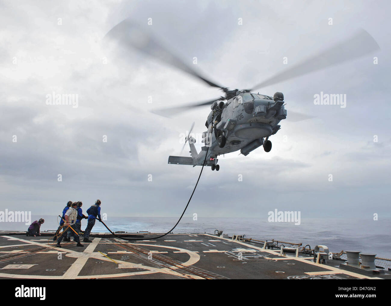 Flight deck crew members conduct a helicopter in-flight refueling Stock ...