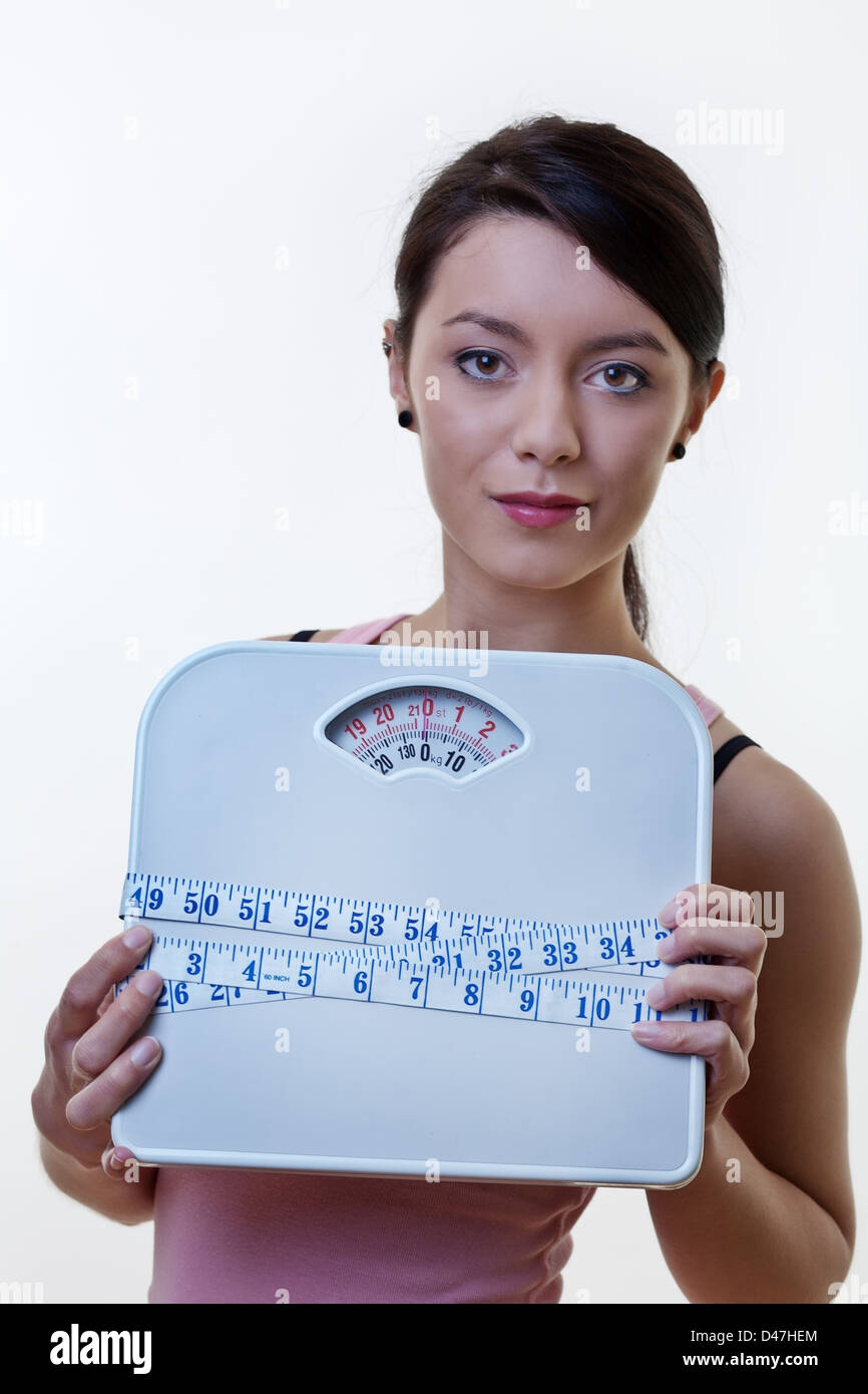 attractive woman holding scales with a tape measure wrapped around them Stock Photo Alamy